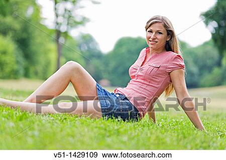 Stock Photo - Portrait of a blonde beautiful woman sitting in the park in Spring. Fotosearch