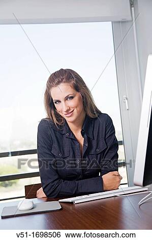 Stock Photograph - Portrait of a blonde woman at workplace with the computer. Fotosearch