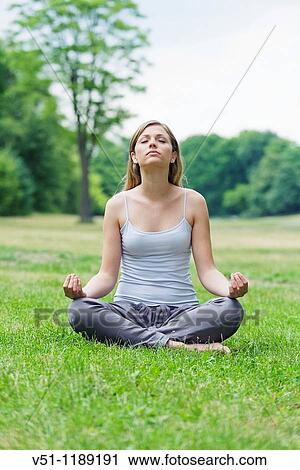 Stock Image - Portrait of a blonde woman doing yoga in the park. Fotosearch