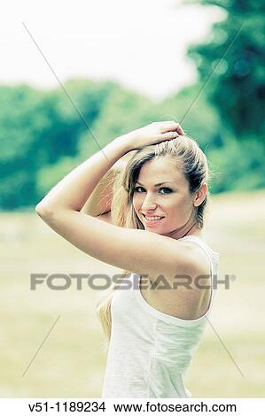 Portrait of a blonde woman holding her hair in the park and smiling at camera View Large Photo Image Picture - Portrait of a blonde woman holding her hair in the park and smiling at camera. Fotosearch