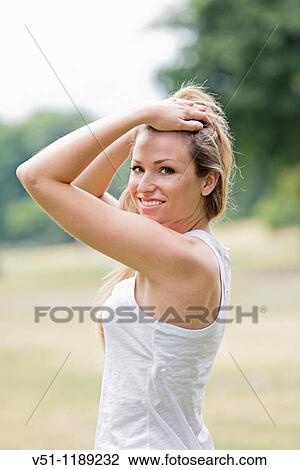 Portrait of a blonde woman holding her hair in the park and smiling at camera View Large Photo Image Stock Image - Portrait of a blonde woman holding her hair in the park and smiling at camera. Fotosearch