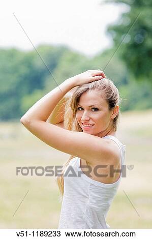 Portrait of a blonde woman holding her hair in the park and smiling at camera View Large Photo Image Stock Image - Portrait of a blonde woman holding her hair in the park and smiling at camera. Fotosearch