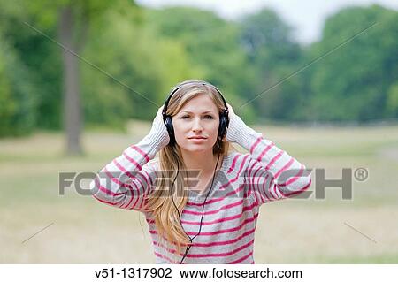 Portrait of a blonde woman listening to music in the park, looking at camera View Large Photo Image Stock Image - Portrait of a blonde woman listening to music in the park, looking at camera. Fotosearch