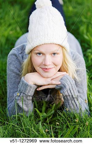 Stock Photo - Portrait of a blonde woman lying down in teh park smiling at camera. Fotosearch