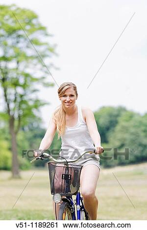 Stock Image - Portrait of a blonde woman riding a bike in the park. Fotosearch