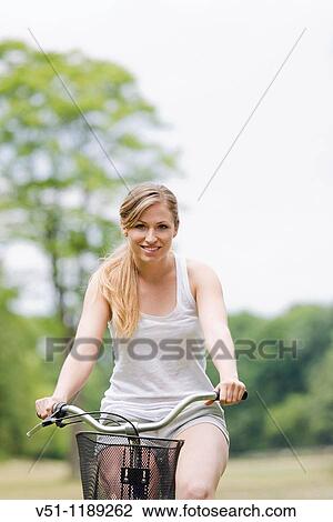 Portrait of a blonde woman riding a bike in the park View Large Photo Image Stock Image - Portrait of a blonde woman riding a bike in the park. Fotosearch