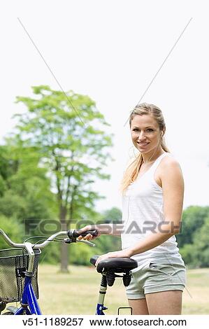 Stock Photo - Portrait of a blonde woman riding a bike in the park. Fotosearch