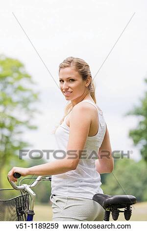 Portrait of a blonde woman riding a bike in the park View Large Photo Image Stock Photo - Portrait of a blonde woman riding a bike in the park. Fotosearch