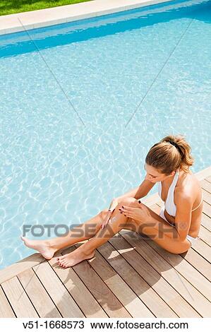 Portrait of a blonde woman sitting by the pool using suncream View Large Photo Image Stock Image - Portrait of a blonde woman sitting by the pool using suncream. Fotosearch