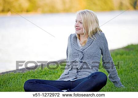 Portrait of a blonde woman sitting in the park looking at the water and smiling View Large Photo Image Stock Image - Portrait of a blonde woman sitting in the park looking at the water and smiling. Fotosearch