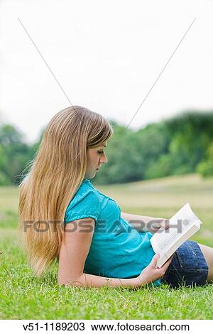 Stock Image - Portrait of a blonde woman with a book in the park. Fotosearch
