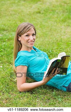 Portrait of a blonde woman with a book in the park looking at camera View Large Photo Image Stock Photograph - Portrait of a blonde woman with a book in the park looking at camera. Fotosearch