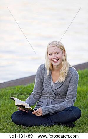 Portrait of a blonde young woman reading a book and smiling at camera View Large Photo Image Stock Image - Portrait of a blonde young woman reading a book and smiling at camera. Fotosearch