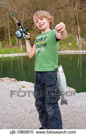 Stock Image - Portrait of a boy with a recently caught trout. Slovenia.. Fotosearch