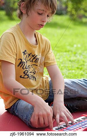 Portrait of a boy with keyboard playing outdoor in the garden. View Large Photo Image Picture - Portrait of a boy with keyboard playing outdoor in the garden.. Fotosearch