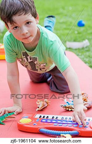 Portrait of a boy with keyboard playing outdoor in the garden. View Large Photo Image Picture - Portrait of a boy with keyboard playing outdoor in the garden.. Fotosearch
