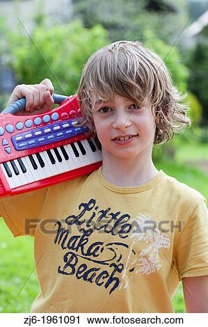 Portrait of a boy with keyboard playing outdoor in the garden. View Large Photo Image Stock Image - Portrait of a boy with keyboard playing outdoor in the garden.. Fotosearch