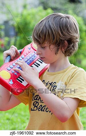Portrait of a boy with keyboard playing outdoor in the garden. View Large Photo Image Stock Image - Portrait of a boy with keyboard playing outdoor in the garden.. Fotosearch