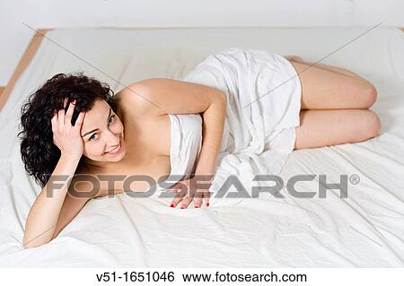Stock Photograph - Portrait of a brunette beautiful and sexy woman in bed. Fotosearch
