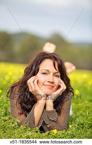 Portrait of a brunette woman lying in grass smiling at camera View Large Photo Image Picture - Portrait of a brunette woman lying in grass smiling at camera. Fotosearch