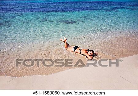 Stock Image - Portrait of a brunette woman relaxing at the beach in Formentera. Fotosearch