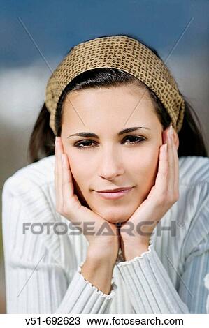 Stock Image - Portrait of a brunette young woman in the park. Fotosearch