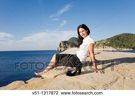 Stock Image - Portrait of a business woman relaxing in a cliff. Fotosearch