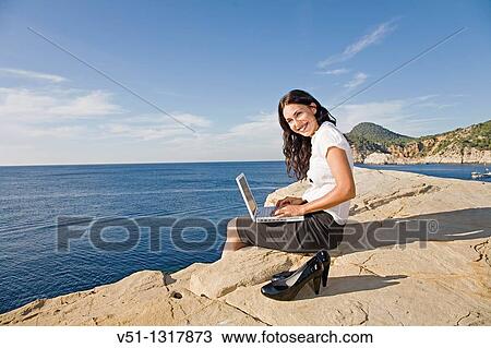 Stock Image - Portrait of a business woman with laptop in a cliff. Fotosearch