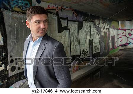 Picture - Portrait of a businessman in a walkway covered with grafitti. Fotosearch