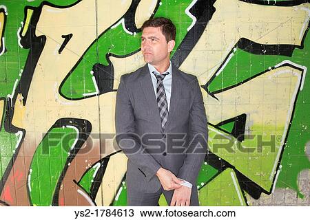 Portrait of a businessman standing in front of wall covered with grafitti View Large Photo Image Stock Image - Portrait of a businessman standing in front of wall covered with grafitti. Fotosearch
