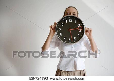 Portrait of a businesswoman hiding her face behind a clock View Large Photo Image Stock Image - Portrait of a businesswoman hiding her face behind a clock. Fotosearch
