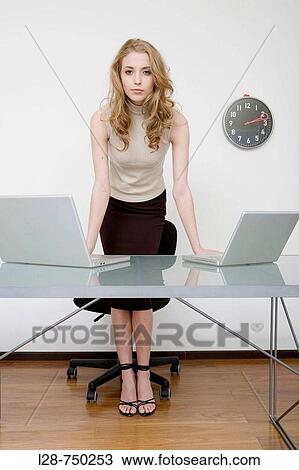 Stock Image - Portrait of a businesswoman leaning against the table. Fotosearch