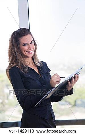 Portrait of a businesswoman with agenda by the window smiling at camera View Large Photo Image Stock Image - Portrait of a businesswoman with agenda by the window smiling at camera. Fotosearch