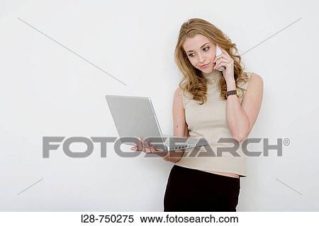 Portrait of a businesswoman working on a laptop and answering telephone View Large Photo Image Stock Photography - Portrait of a businesswoman working on a laptop and answering telephone. Fotosearch