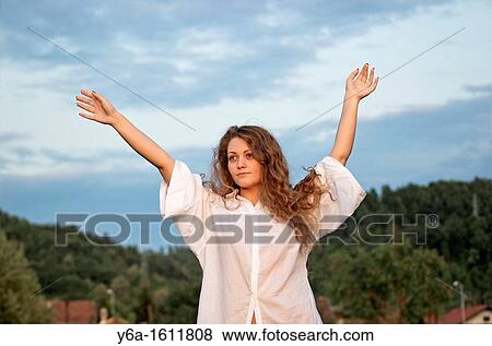 Portrait of a content young woman outdoors with arms raised View Large Photo Image Stock Photo - Portrait of a content young woman outdoors with arms raised. Fotosearch