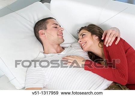 Stock Photo - Portrait of a couple at home in love relaxing in the sofa. Fotosearch