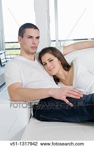 Stock Image - Portrait of a couple at home relaxing in the sofa. Fotosearch