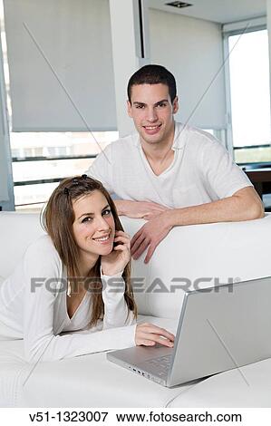 Portrait of a couple chilling in sofa with laptop View Large Photo Image Stock Photo - Portrait of a couple chilling in sofa with laptop. Fotosearch