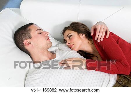 Stock Image - Portrait of a couple in sofa in love looking at each other. Fotosearch