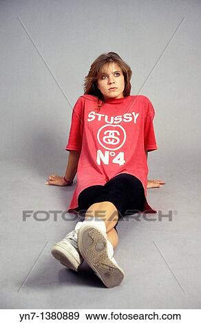 Stock Photo - Portrait of a girl sitting on the studio floor with a slight look of contenation. Fotosearch