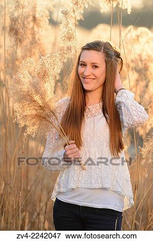 Portrait of a good looking young woman in the reeds at sunset in early spring. View Large Photo Image Stock Photo - Portrait of a good looking young woman in the reeds at sunset in early spring.. Fotosearch