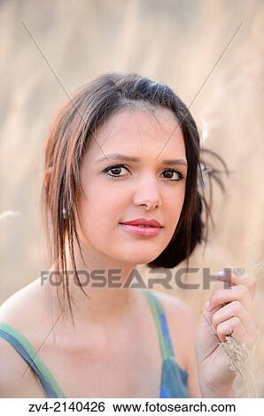 Portrait of a good looking young woman in the grass in early spring. View Large Photo Image Stock Photograph - Portrait of a good looking young woman in the grass in early spring.. Fotosearch