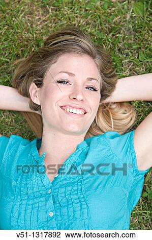 Portrait of a happy blonde woman lying down in the park View Large Photo Image Stock Image - Portrait of a happy blonde woman lying down in the park. Fotosearch