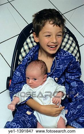 Portrait of a happy boy holding his new baby sister for the first time View Large Photo Image Stock Photo - Portrait of a happy boy holding his new baby sister for the first time. Fotosearch