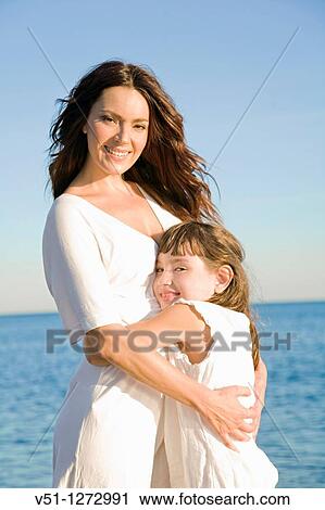 Stock Image - Portrait of a mother embracing her daughter at the beach. Fotosearch