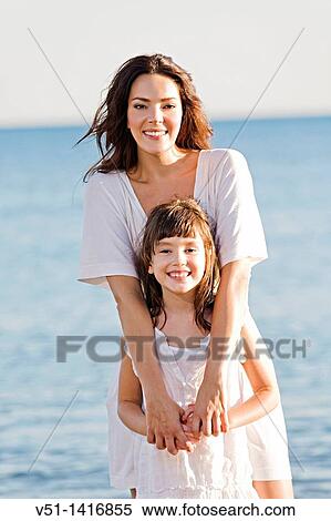 Portrait of a mother embracing her daughter at the beach View Large Photo Image Stock Photography - Portrait of a mother embracing her daughter at the beach. Fotosearch