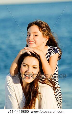 Portrait of a mother with her daughter smiling at the beach View Large Photo Image Stock Image - Portrait of a mother with her daughter smiling at the beach. Fotosearch