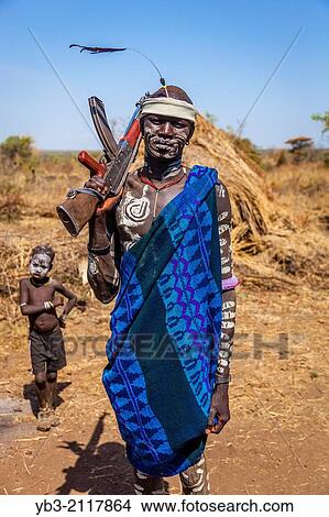 Picture - Portrait Of A Mursi Man Holding a Gun, Mursi Tribal Village, The Omo Valley, Ethiopia.. Fotosearch
