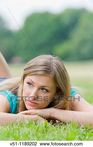 Portrait of a pensive woman lying down in park View Large Photo Image Stock Image - Portrait of a pensive woman lying down in park. Fotosearch