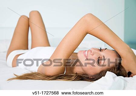 Stock Photo - Portrait of a pretty blonde woman lying in bed. Fotosearch